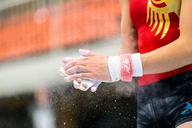 Nahaufnahme von Händen eines Turners mit Chalk, die vor einem Wettkampf im Gymnastik bereitgemacht werden.